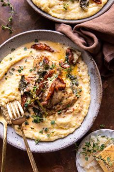 two bowls filled with mashed potatoes topped with meat and herbs next to a fork