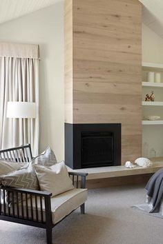 a living room filled with furniture and a fire place in front of a wooden wall