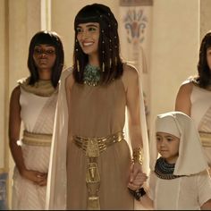 two women in egyptian garb holding hands with a little boy dressed as anub