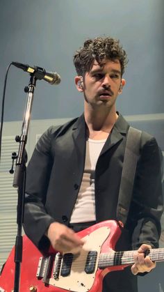 a man with a red guitar standing in front of a microphone