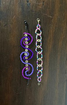 two beaded bracelets sitting on top of a wooden table next to each other