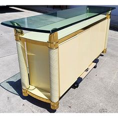 a table that is on wheels with a glass top and gold trim around the edges