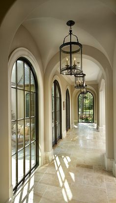 a large hallway with arched windows and chandelier hanging from it's ceiling