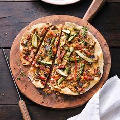 a pizza sitting on top of a wooden cutting board next to a knife and fork