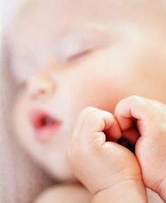 a close up of a baby's face with its hands on the side of her head