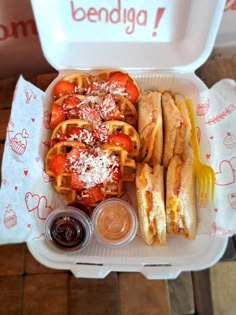 a waffle with cheese and tomatoes on it next to some condiments in a styrofoam container