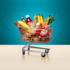 a shopping cart filled with lots of different types of fruits and vegetables in front of a blue background