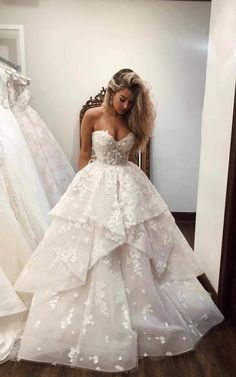 a woman in a white wedding dress standing next to two dresses on mannequins