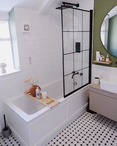 a white bath tub sitting under a bathroom mirror