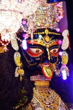 an elaborately decorated mask is displayed in front of the camera, with lights behind it