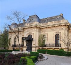 a large building with many windows and bushes around it