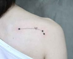 the back of a woman's shoulder with an arrow and stars tattoo on it