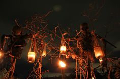 halloween decorations are lit up at night in the dark with lanterns hanging from branches and pumpkins on them