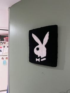 a black and white bunny patch hanging on the side of a wall next to a refrigerator