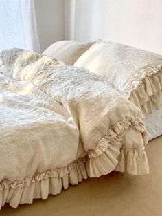 an unmade bed with white sheets and ruffles