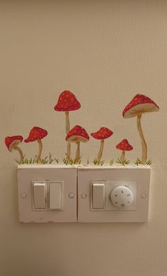 some red mushrooms are sitting on top of a light switch cover in the bathroom wall