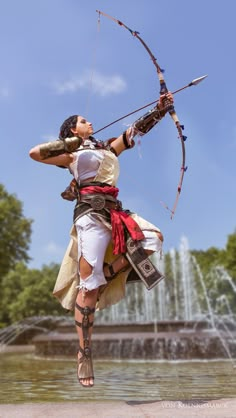 a woman dressed in costume is holding a bow and arrow