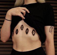 a woman with tattoos on her stomach posing for the camera while wearing a black top