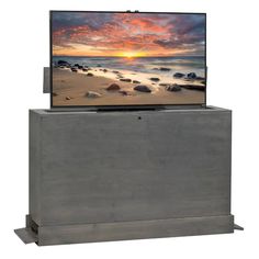 a flat screen tv sitting on top of a wooden stand next to the ocean at sunset