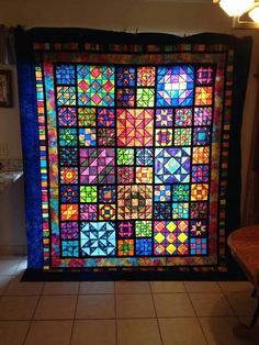 a colorful quilt is hanging on the wall in a room with tile flooring and white walls