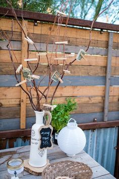 a vase with some money in it sitting on a wooden table next to a potted plant