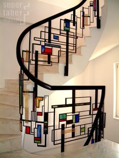 a spiral staircase in a home with white walls and marble steps, painted with multicolored squares