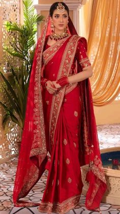 a woman wearing a red sari and gold jewelry