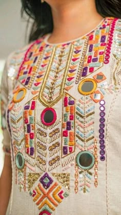 a close up of a woman wearing a dress with beads on the neck and shoulders