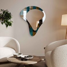 a living room with two white chairs and a round coffee table in front of a mirror