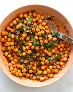 a bowl filled with chickpeas and spinach on top of a white table