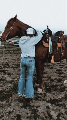 a woman standing next to a brown horse