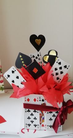 a gift box filled with playing cards and red ribbon tied to it's sides