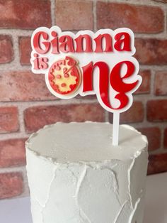 a white cake topped with a red and yellow sign that says giana is one