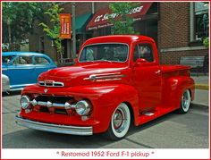 an old red truck parked in front of a building