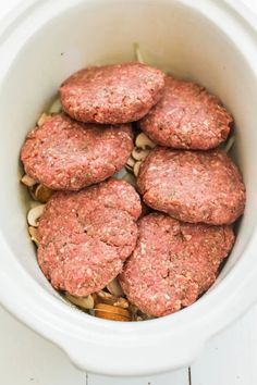 several hamburger patties in a white crockpot with nuts on the side, ready to be eaten