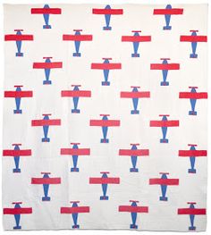 a red, white and blue quilt with an airplane pattern on it's side