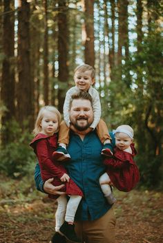 a man holding two children in the woods