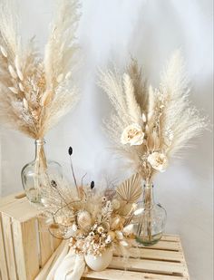 two vases filled with dried flowers on top of a wooden crate