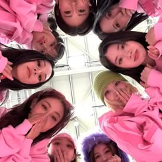 a group of young women standing in a circle with their hands on their mouths and looking up at the camera