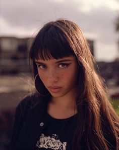 a young woman with freckles on her face and long brown hair is looking at the camera