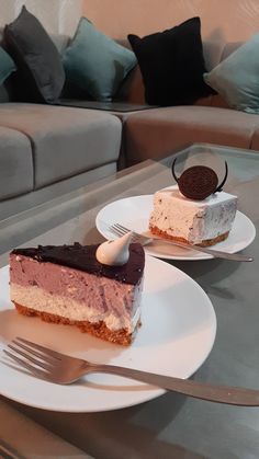 two pieces of cake sitting on top of white plates with silverware in front of them