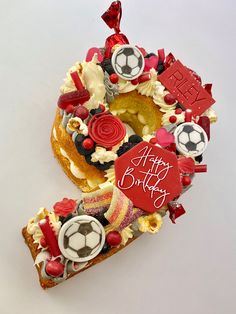 a birthday cake decorated with soccer balls and other sports related items is displayed on a white surface