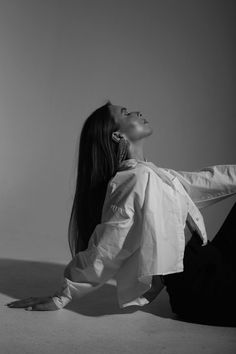 a woman is sitting on the floor with her legs crossed and looking up to the sky