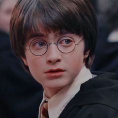 a young boy wearing glasses and a tie in front of some other people at a graduation ceremony