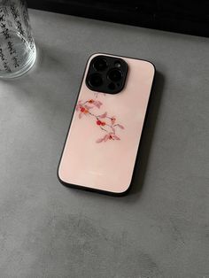 a pink phone case sitting on top of a table next to a glass cup with water in it