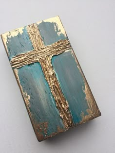 an old wooden box with a cross painted on the front and sides, sitting on a white surface