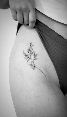 a woman's stomach with a small flower tattoo on the side of her thigh