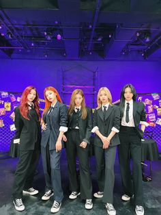 four young women in suits and ties posing for a photo with each other on stage