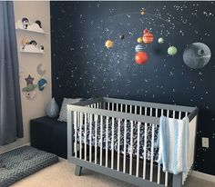 a baby's room with planets and stars painted on the wall, including a crib