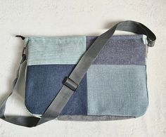 a cross body bag made out of patchwork fabric and leather straps, sitting on a white surface